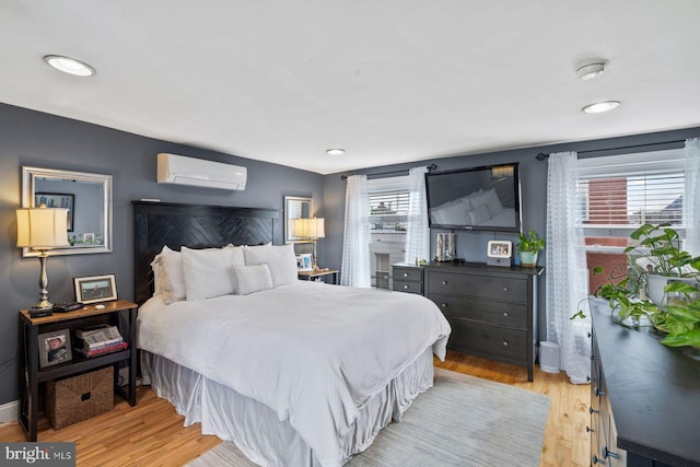 bedroom with light hardwood / wood-style floors and a wall unit AC