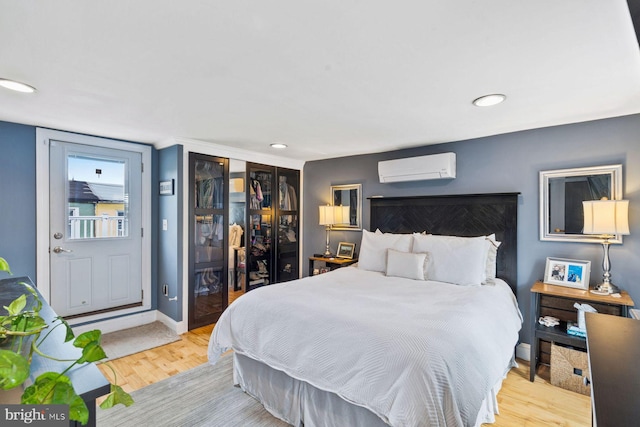 bedroom featuring light wood-type flooring and an AC wall unit