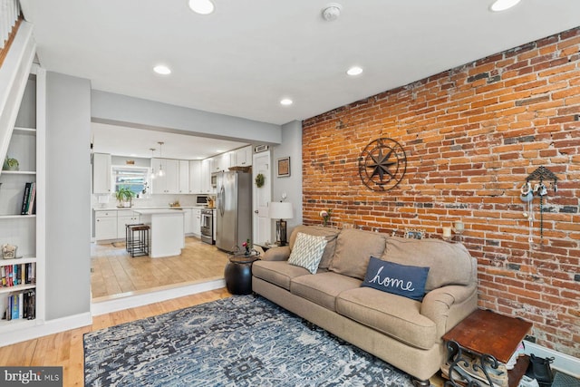 living room with brick wall and light wood-type flooring