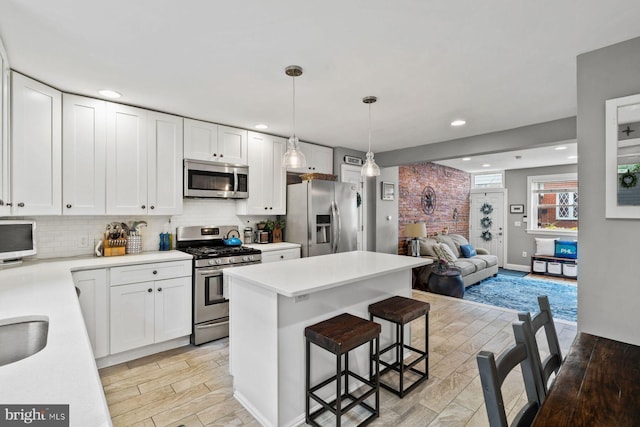 kitchen featuring appliances with stainless steel finishes, hanging light fixtures, tasteful backsplash, and white cabinetry