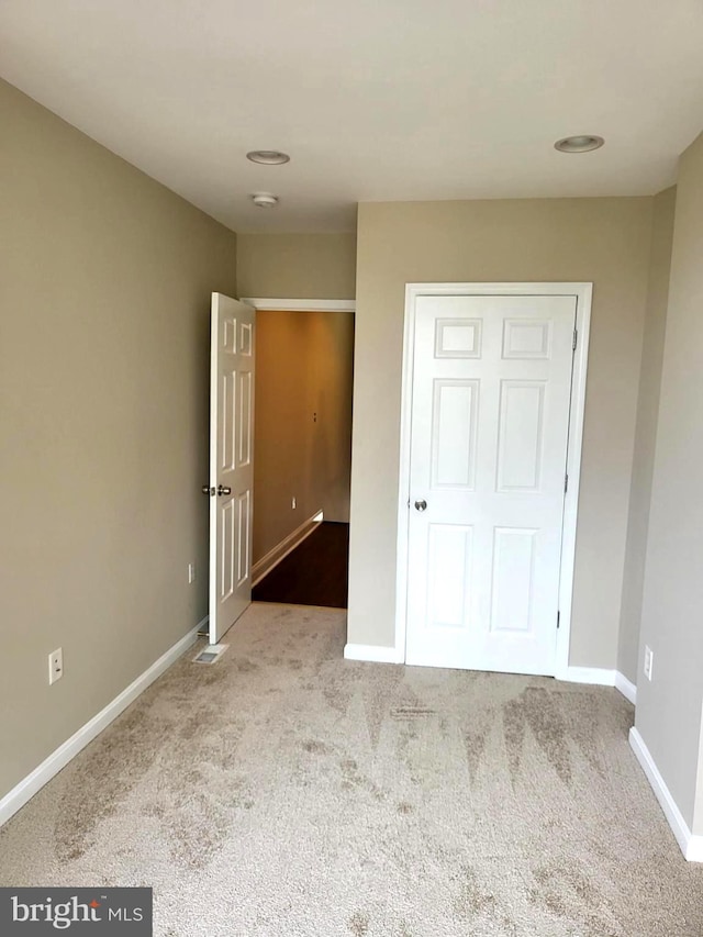 unfurnished bedroom featuring light colored carpet and a closet