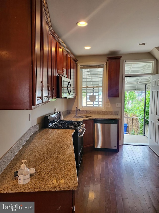 kitchen featuring appliances with stainless steel finishes, sink, dark wood-type flooring, and light stone counters