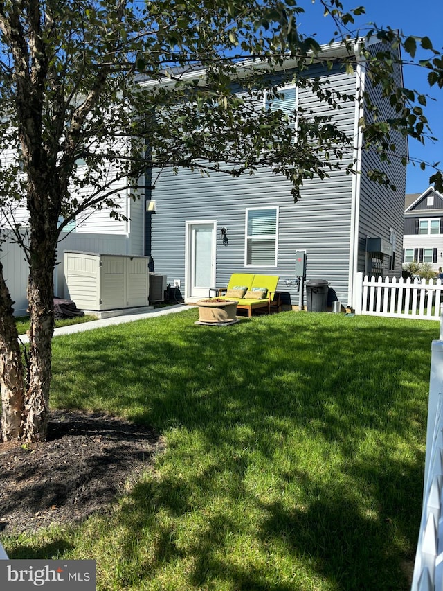 back of property with central air condition unit, a storage shed, and a yard