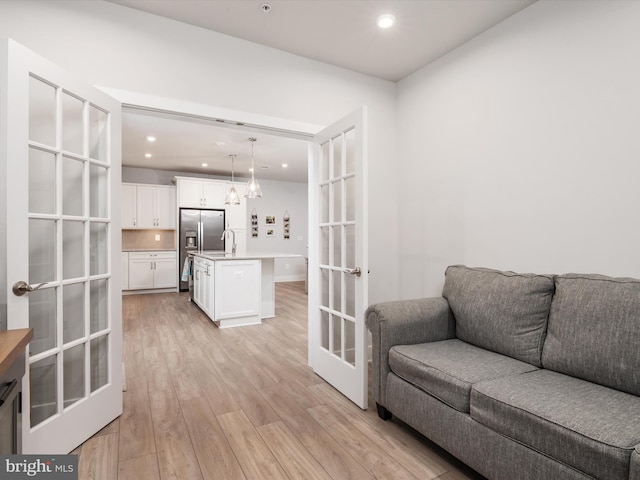 living room featuring french doors, light hardwood / wood-style flooring, and sink