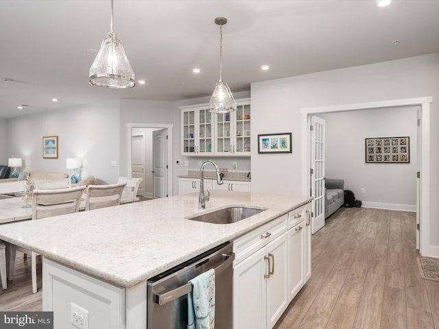 kitchen with light hardwood / wood-style floors, sink, white cabinets, hanging light fixtures, and stainless steel dishwasher