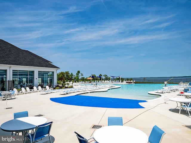 view of swimming pool featuring a water view and a patio area