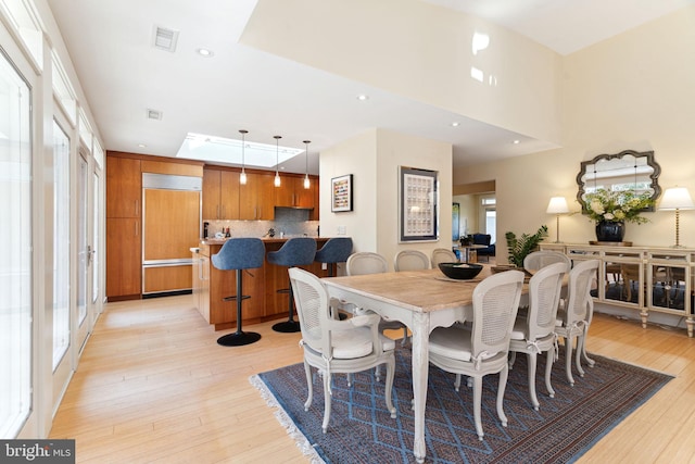 dining room with a towering ceiling and light hardwood / wood-style flooring