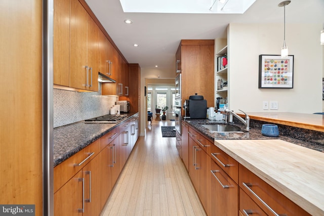 kitchen with butcher block countertops, a skylight, light wood-type flooring, and sink