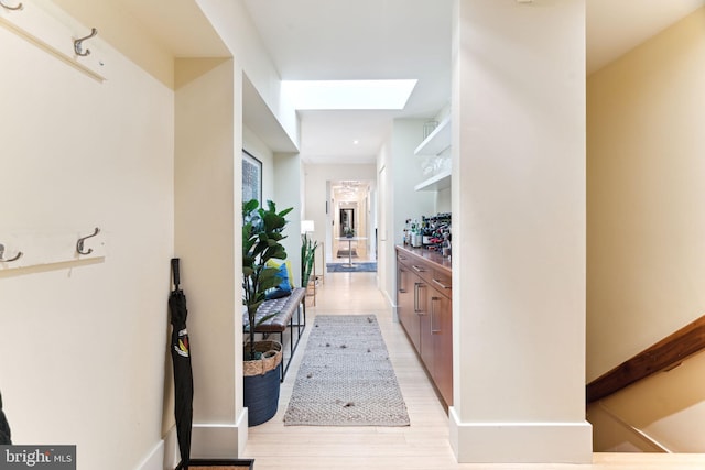 hall with light wood-type flooring and a skylight