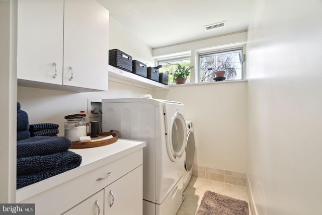 laundry area with cabinets, independent washer and dryer, and light tile patterned floors