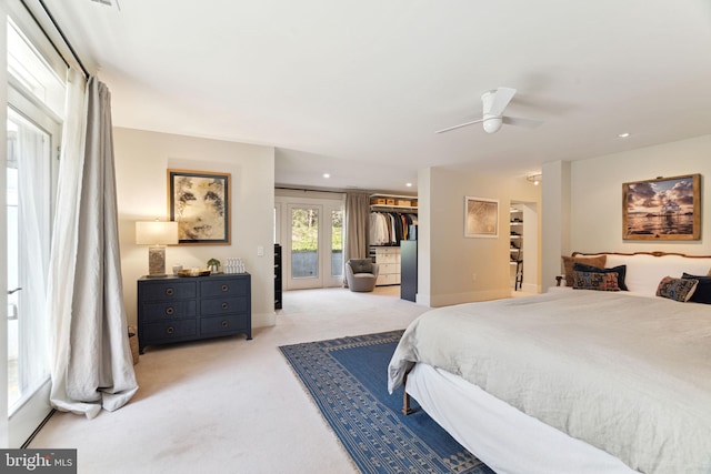 bedroom with a spacious closet, light carpet, ceiling fan, and a closet