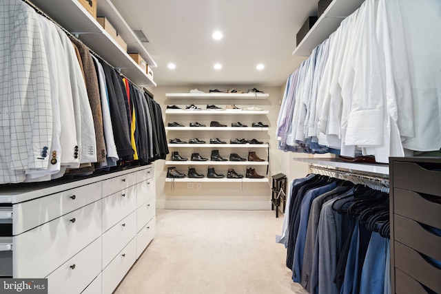 walk in closet with light carpet