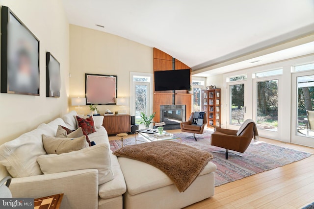 living room featuring french doors, a fireplace, light hardwood / wood-style floors, and high vaulted ceiling