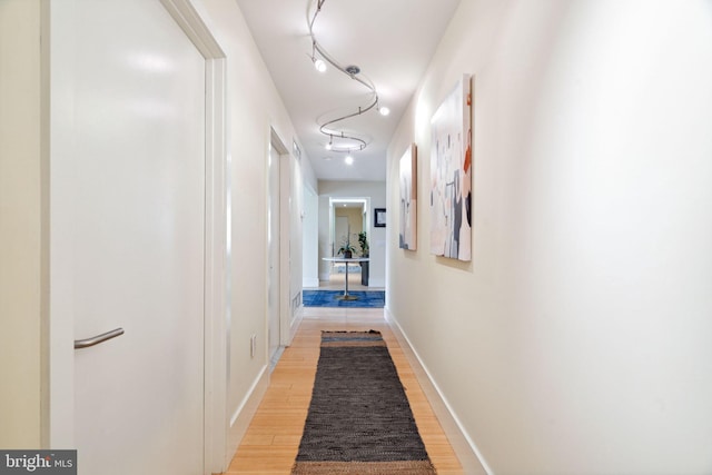 hallway featuring light wood-type flooring and track lighting