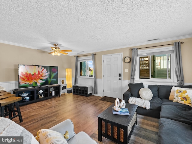 living room with ornamental molding, dark hardwood / wood-style flooring, a textured ceiling, and ceiling fan