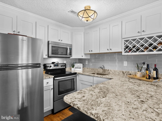 kitchen with hardwood / wood-style floors, appliances with stainless steel finishes, sink, and white cabinetry