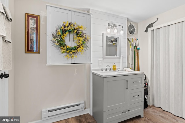 bathroom with wood-type flooring, vanity, and a baseboard heating unit