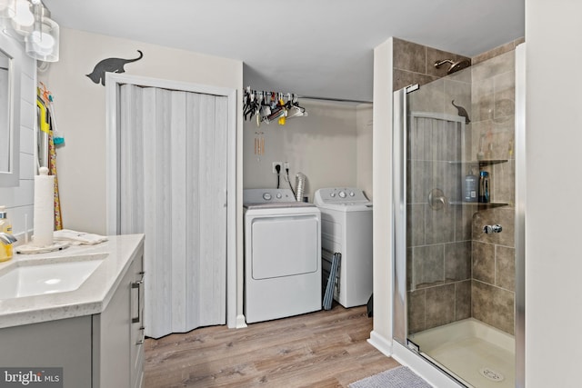 bathroom with a tile shower, vanity, hardwood / wood-style floors, and independent washer and dryer