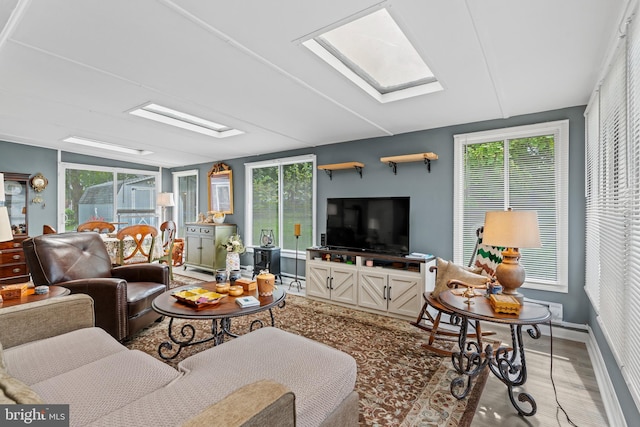 living room featuring a healthy amount of sunlight, hardwood / wood-style floors, and a skylight