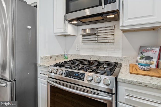 kitchen with light stone counters, white cabinets, and appliances with stainless steel finishes