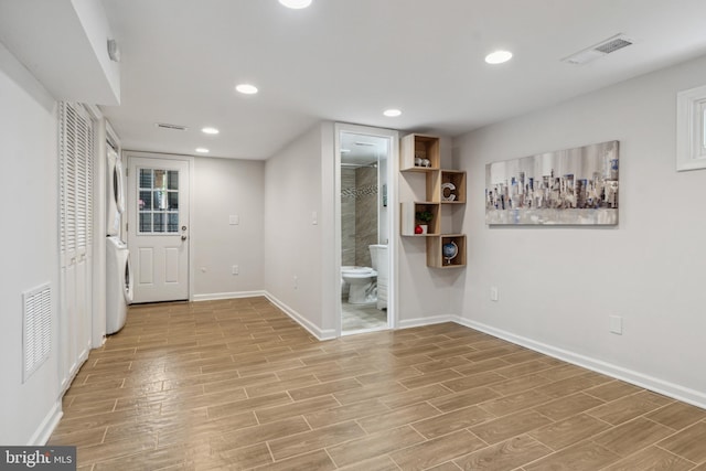 interior space with light hardwood / wood-style floors and stacked washing maching and dryer