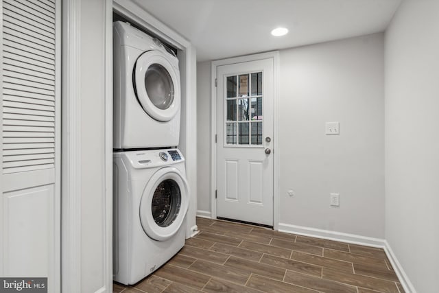 laundry area featuring stacked washer and clothes dryer and dark hardwood / wood-style flooring