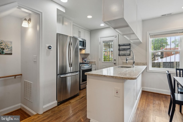 kitchen featuring appliances with stainless steel finishes, a healthy amount of sunlight, kitchen peninsula, and white cabinetry