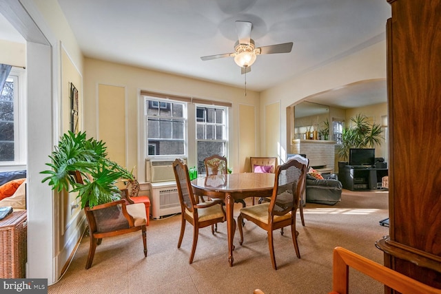 carpeted dining area featuring cooling unit, a fireplace, and ceiling fan