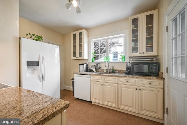 kitchen featuring sink, white appliances, light stone countertops, and cream cabinetry