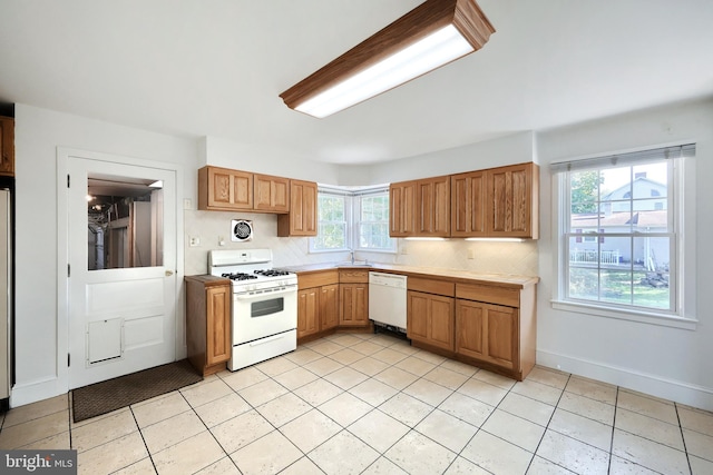 kitchen featuring white appliances, backsplash, sink, and a healthy amount of sunlight