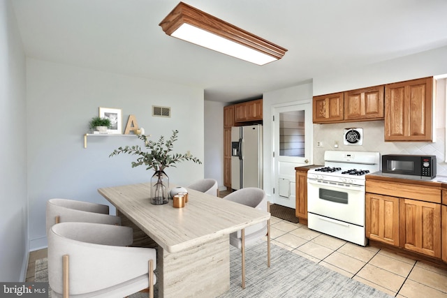 kitchen featuring light tile patterned flooring, white appliances, and decorative backsplash