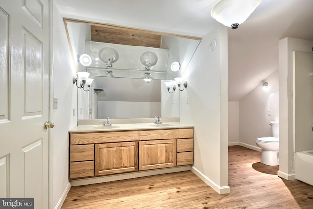 bathroom featuring hardwood / wood-style flooring, toilet, lofted ceiling, and vanity