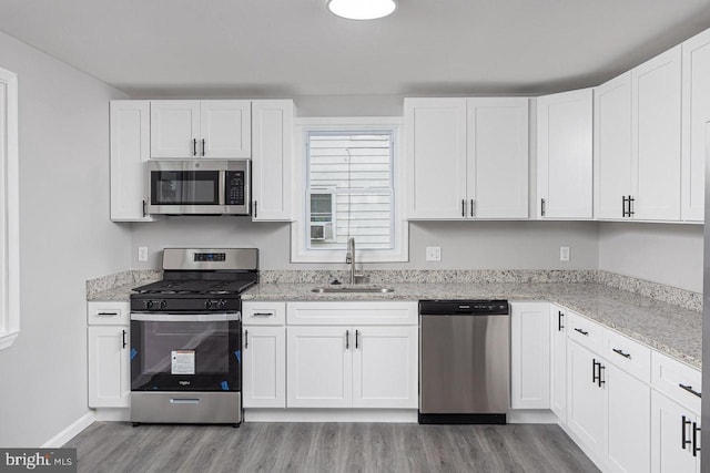 kitchen with light hardwood / wood-style floors, white cabinetry, sink, and stainless steel appliances