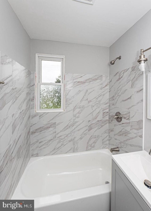 bathroom featuring tiled shower / bath combo and vanity