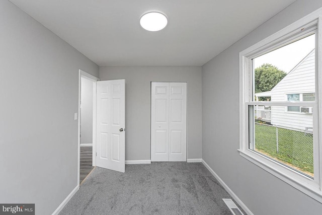 unfurnished bedroom featuring multiple windows, a closet, and light colored carpet