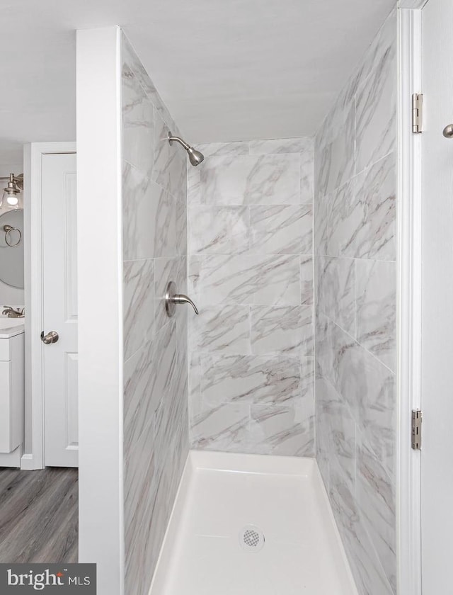 bathroom featuring hardwood / wood-style flooring and a tile shower