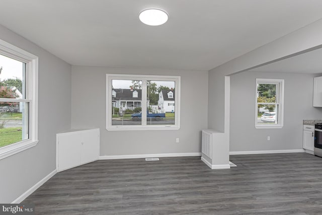 unfurnished living room with dark wood-type flooring and a healthy amount of sunlight