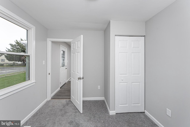 unfurnished bedroom with a closet and dark carpet