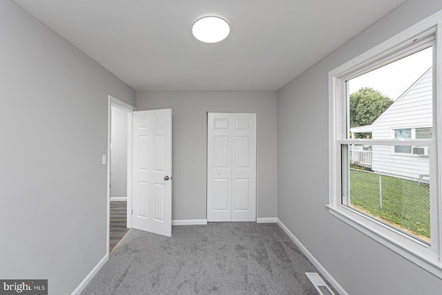 unfurnished bedroom with multiple windows, a closet, and light colored carpet