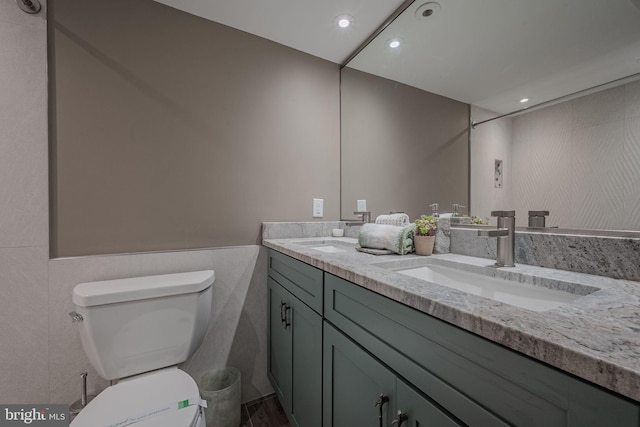 bathroom with tile walls, vanity, and toilet