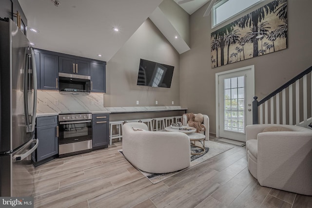 living room featuring stairs, a high ceiling, recessed lighting, and light wood finished floors