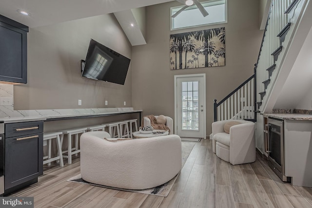 living room with a high ceiling, light hardwood / wood-style floors, and ceiling fan