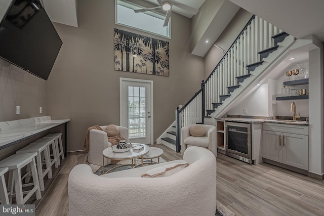 living room with indoor wet bar, light wood-type flooring, wine cooler, and a high ceiling