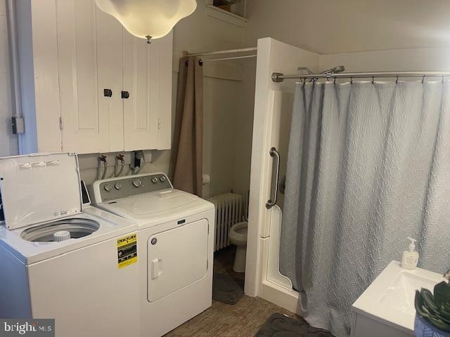 washroom with washer and clothes dryer, radiator heating unit, and hardwood / wood-style flooring