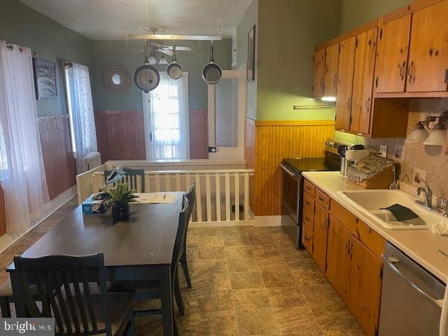 kitchen featuring decorative backsplash, stainless steel appliances, sink, and wooden walls