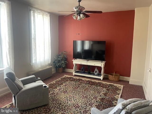 carpeted living room with radiator heating unit, a healthy amount of sunlight, and ceiling fan