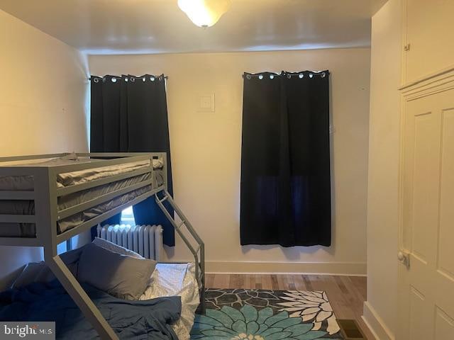 bedroom with radiator heating unit and wood-type flooring