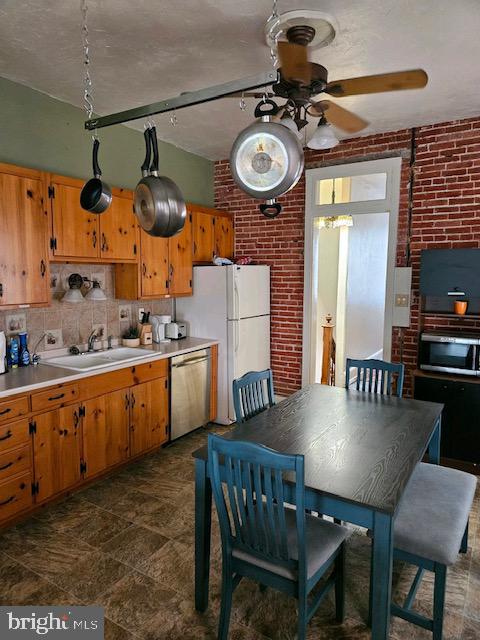 kitchen with stainless steel dishwasher, brick wall, sink, and tasteful backsplash