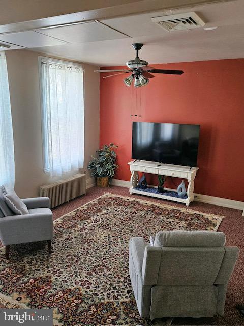 living room with ceiling fan, carpet flooring, and radiator heating unit