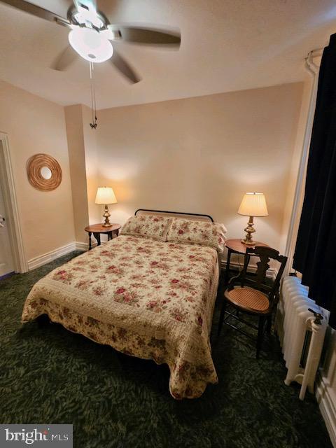 carpeted bedroom with radiator and ceiling fan